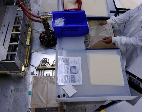 Technician feeding plastic formed pieces into an RF welding machine.
