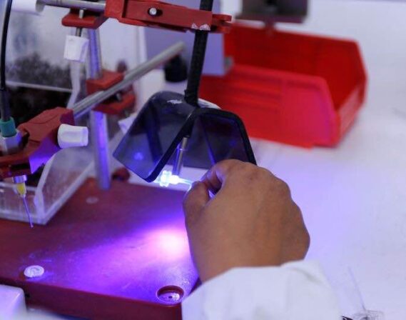 technician holding a medical device under a uv curing tool