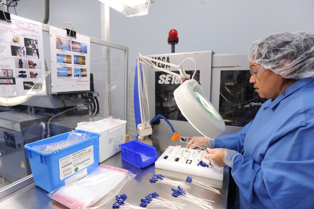 Clean room technician looking through a magnifying glass in Providien's assembly plant in Tijuana, Mexico.